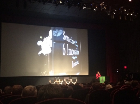 Jennifer Davis presenting on stage at a conference, beside a large screen.